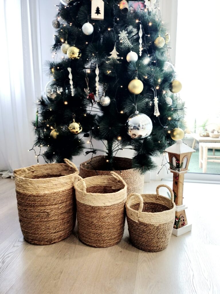 3 cestas redondas de fibras naturales en dos tonos marrones delante de un arbol de Navidad